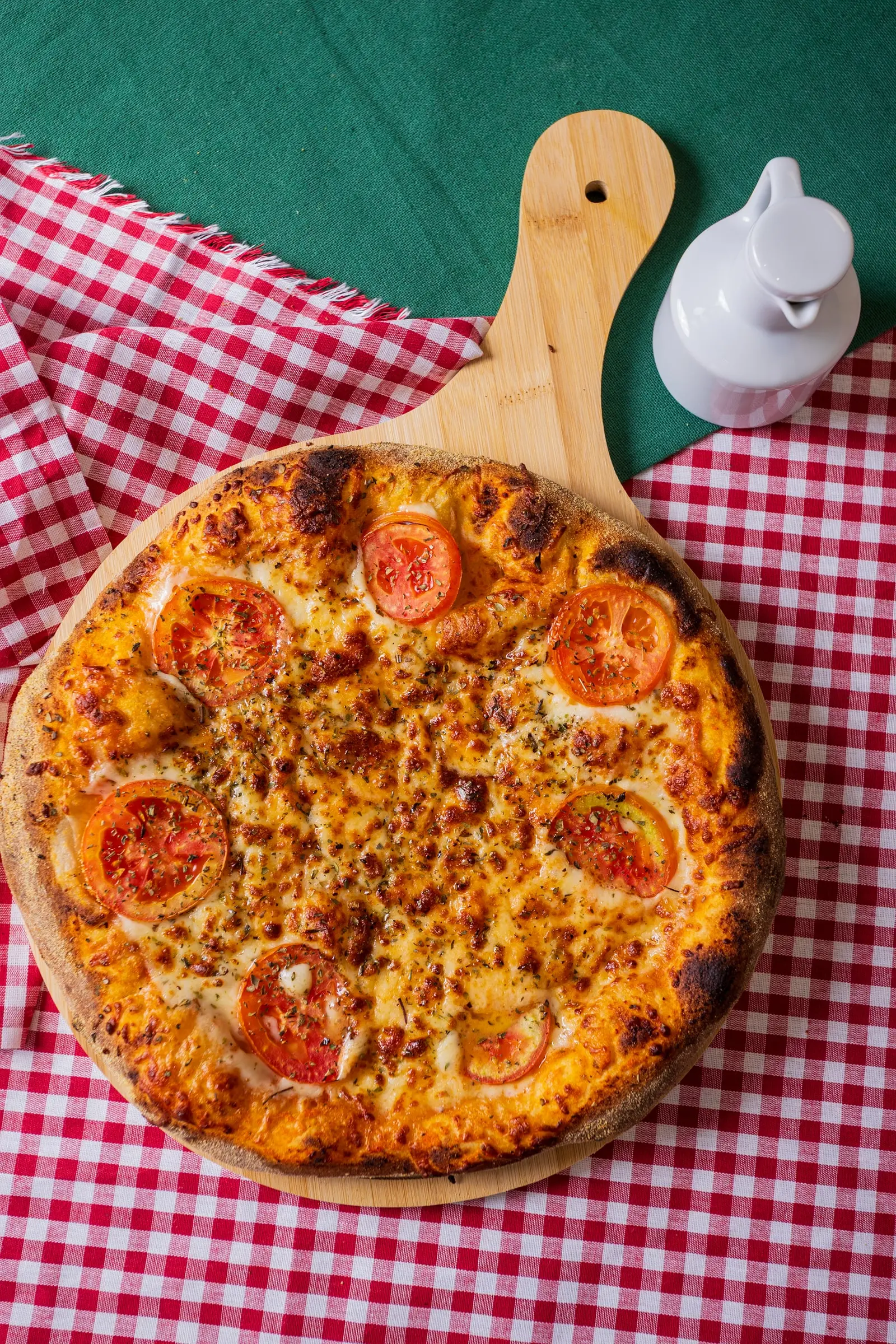 Pizza margherita inteira com rodelas de tomate, sobre a tábua